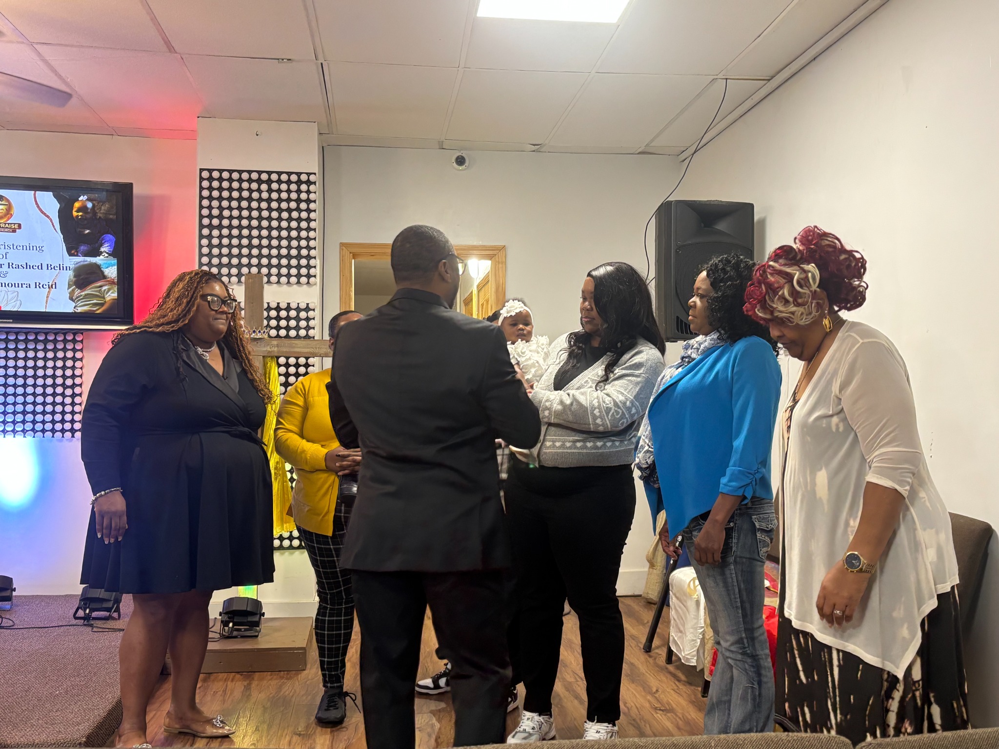 Church leaders and family praying during a christening service